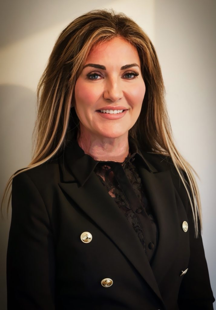 Dawn Taylor smiling with a Black blazer and gold buttons