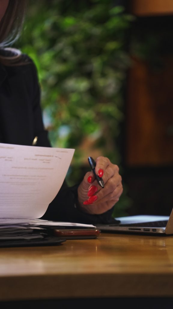 Dawn Taylor signing agreements sitting at her desk with a pen and holding a document
